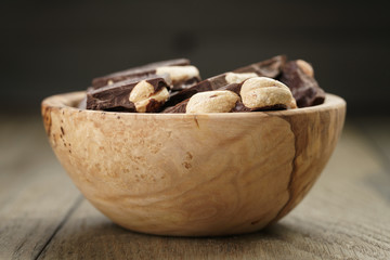 broken homemade bar of chocolate with cashew nuts in wood bowl