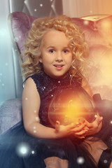 Cute little blond girl sitting in a chair of classic style 