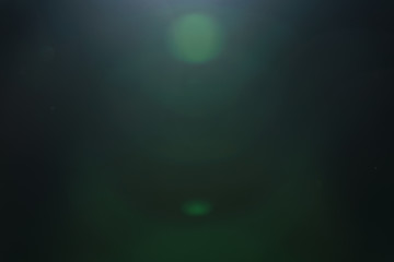 real green lens flare over dark background