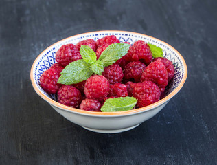 Fresh ripe raspberries in a bowl with mint