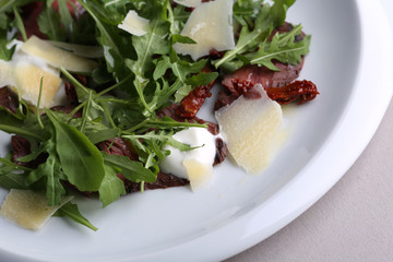 Salad with beef, arugula, cheese and creamy sauce. Close up