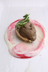 Pate with herbs and sauce on a white plate, closeup