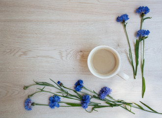 Obraz na płótnie Canvas Blue cornflowers and a cup of coffee on wooden background. Overhead view. Flat lay, top view. Place for your text.