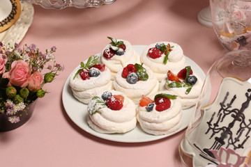 Obraz na płótnie Canvas Meringue nests with strawberry cream, fresh strawberries, raspberries, blueberries and a mint leaf