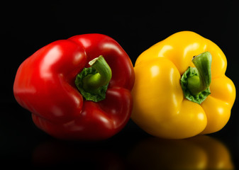 Fresh red and yellow peppers. On a black background