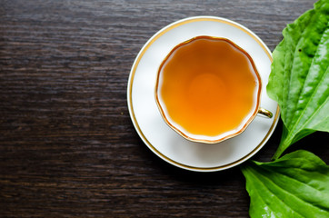 herbal plantain tea in a porcelain Cup on a dark wooden background