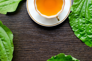 herbal plantain tea in a porcelain Cup on a dark wooden background