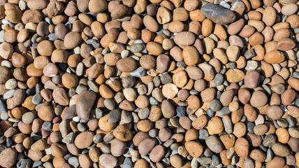 Small stones on the ground with the sun shining.