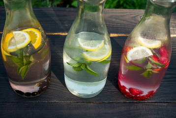 Three glass bottles with drink of mint and berries
