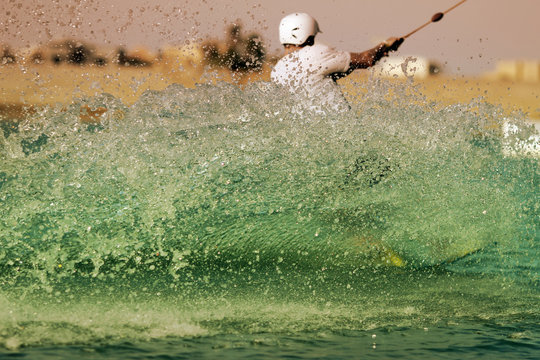 Wakeboarder sportsman in the cablepark makes water splash