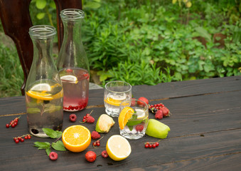 Two glasses and two bottles with drink of mint and berries