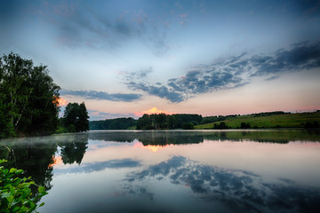 foggy morning sunrise river landscape with trees and clouds