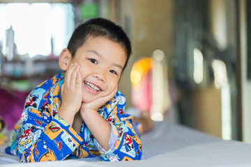 Asian kid laying down on the white bed