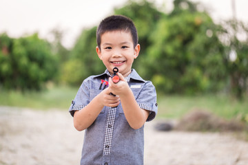 little asian boy playing with a toy gun