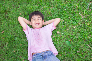 Little boy lay down on the grass with smile face