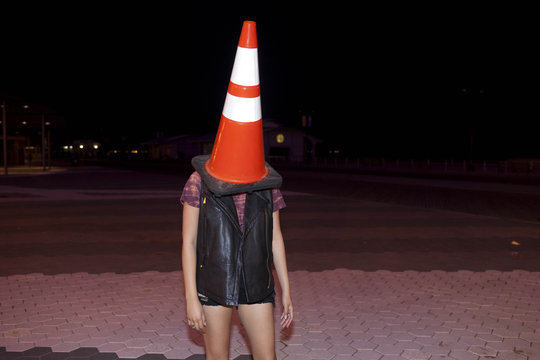 Playful young woman with a traffic cone on her head