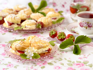 Obraz na płótnie Canvas Cream puffs or profiterole filled with whipped cream served with strawberries on a breakfast table