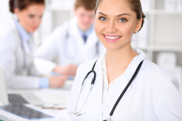 Fototapeta premium Happy doctor woman with medical staff at the hospital sitting at the table and discussing medical history