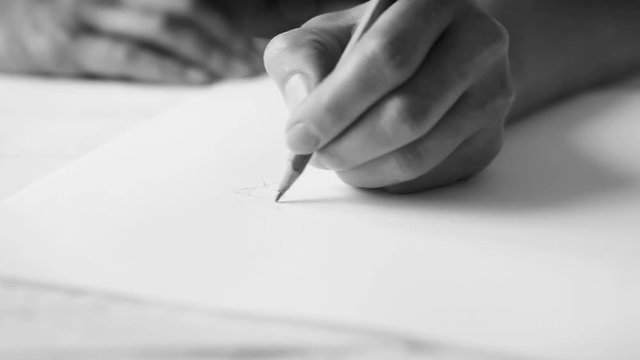 A woman's hand drawing something inspirationally with a graphite pencil