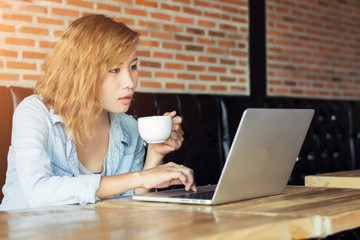 Fototapeta premium Beautiful young hipster woman using laptop at cafe.