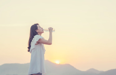 Fototapeta na wymiar beautiful young woman drinking water with sunrise in the morning