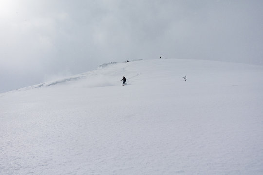 Snowboarder First Tracks Down White Slope of Powder Snow Niseko Hokkaido, Japan