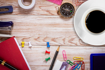 Top view of white coffee cup with office supplies on wood table