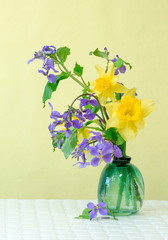 Yellow daffodils in vase with yellow background.