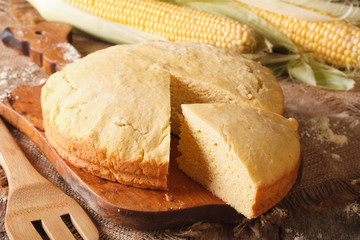Round loaf of corn bread close-up on a wooden board. Horizontal
