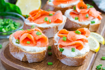 Sandwich with smoked salmon and cream cheese on wooden board