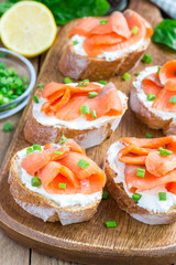 Sandwich with smoked salmon and cream cheese, wooden board, vertical