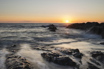Obraz premium Beautiful vibrant sunset landscape image of calm sea against roc