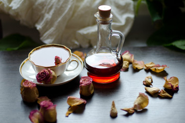 herbal rose tea in a porcelain Cup and Maple syrup on a dark wooden background