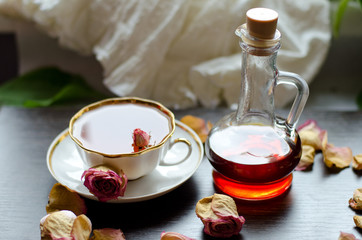 herbal rose tea in a porcelain Cup and Maple syrup on a dark wooden background