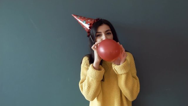 Woman casual style teenage hipster girl blowing inflating a red balloon