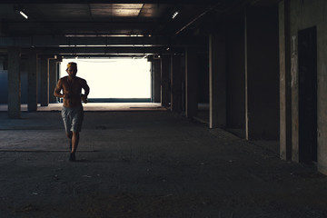 Male athlete running on industrial building, fitness