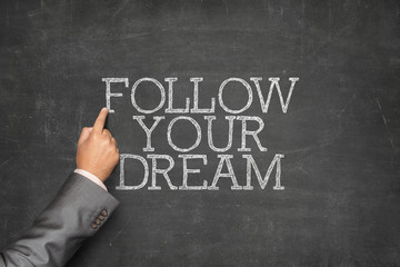 Follow Your Dream text on blackboard with businessman hand pointing