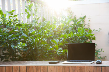 Laptop computer mock up with hard disk on wood texture in garden, right of frame. Relax from...