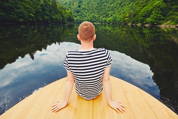 Vacation trip on the river. Handsome man is sitting on the prow of the boat