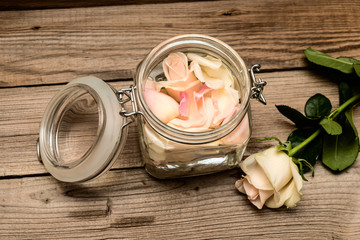  rose water  in a jar and pink rose on a wooden table. Selective focus