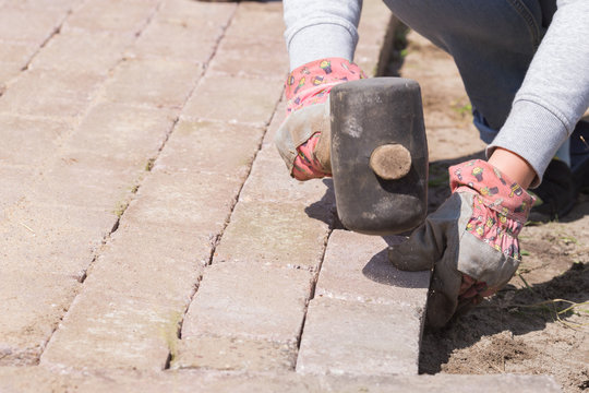 Een vrouw is aan het bestraten in de tuin
