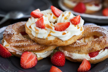 Cream puff rings decorated with fresh strawberry and caramel sau