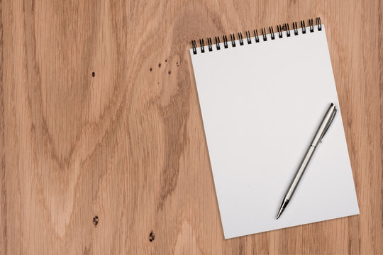 Blank notepad with pen on office wooden table