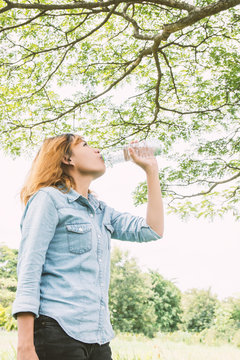 young beautiful  woman drinking water at summer green park.