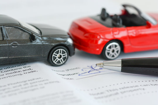 Insurance policy contract concept with toy model cars having a crash or accident 