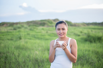 Fototapeta na wymiar Beautiful Asian woman drinking coffee in meadows.