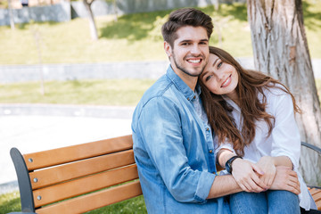 Happy young couple in love sitting on a park bench