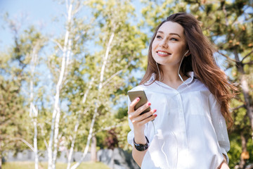 Young happy woman listening music at the park