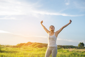 Happy beautiful woman with stretched arms in meadows with fresh