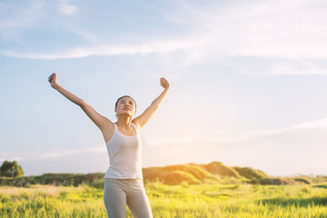 Happy beautiful woman with stretched arms in meadows with fresh